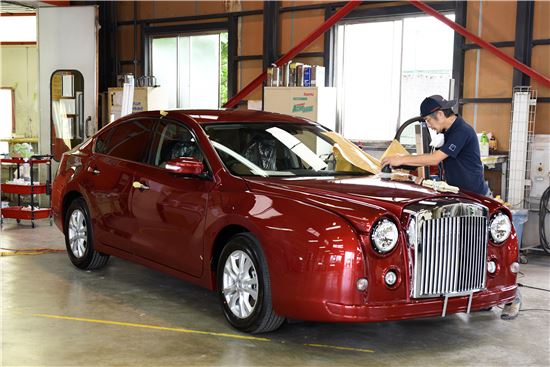 미쓰오카자동차의 한 기술자가 도야마 공장에서 모델 '가류'에 손수 광택을 입히고 있다(사진=블룸버그뉴스).