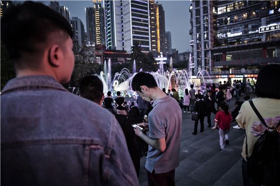 중국 충칭(重慶)의 밤거리에서 한 젊은이가 스마트폰을 들여다보고 있다(사진=블룸버그뉴스).