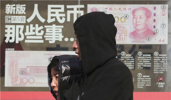 ▲위안화 지폐가 그려진 베이징 시내 한 증권사 앞을 시민들이 지나가고 있다.(사진=AP연합뉴스)