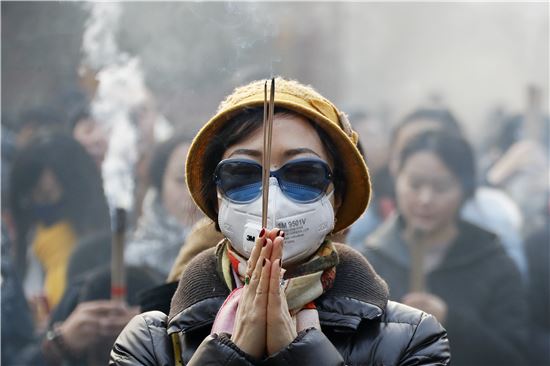 ▲선글라스와 마스크를 쓴 중국 여성이 절 앞에서 향을 피우고 새해 소원을 빌고 있다. (AP=연합뉴스)