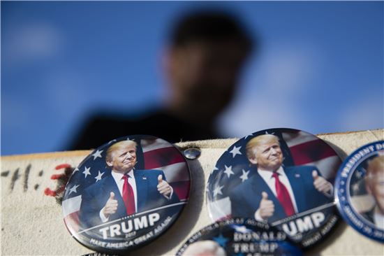 ▲18일(현지시간) 워싱턴 시내에서 한 남성이 도널드 트럼프 대통령 당선자의 얼굴이 그려진 기념품을 판매하고 있다.