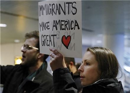28일(현지시간) 포틀랜드 국제공항에서 '이민자들이 미국을 위대하게 만든다'는 문구를 든 여성이 도널드 트럼프 대통령의 반이민 행정명령에 항의하는 시위에 참여하고 있다.(사진=AP연합뉴스) 