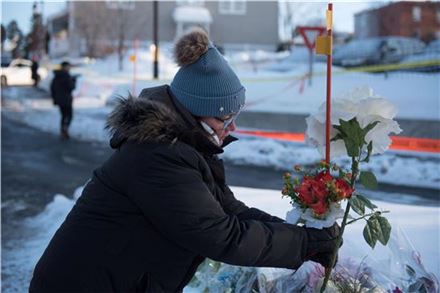 총기테러가 발생한 캐나다 퀘벡 이슬람사원 근처에서 한 시민이 희생자들을 애도하며 꽃을 놓고 있다. 사진=AP연합