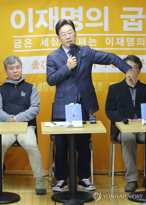 이재명 성남시장이 8일 출판기념회에서 소년공 시절 다쳐서 굽어버린 자신의 팔을 펴 보이고 있다. 사진 / 연합뉴스