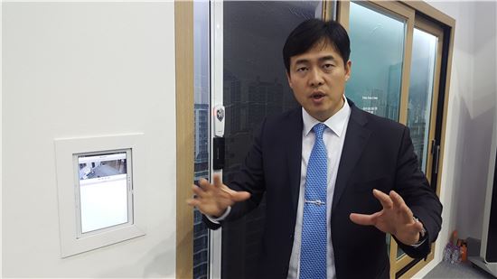 ▲윤준호 성광유니텍 대표가 스마트 방범창 '윈가드'를 배경으로 제품에 대해 설명하고 있다.