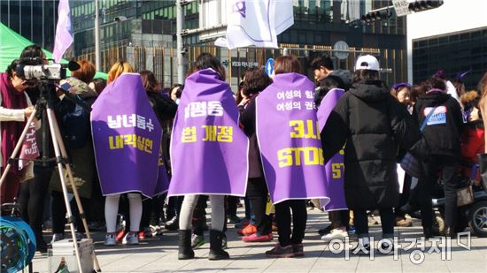 4일 오후 서울 종로 보신각 앞에서 한국여성연합 주최로 열린 '페미니스트가 민주주의를 구한다!' 행사에서 참가자들이 여성의 존엄성을 상징하는 보라색 깃발을 두르고 있다. 