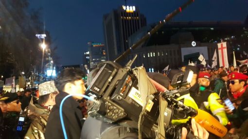 4일 서울 중구 대한문 앞에서 열린 16차 태극기집회에서 흥분한 집회 참가자들이 취재중이던 언론사 카메라기자를 에워싸고 욕설을 퍼부으며 위협하고 있다.
