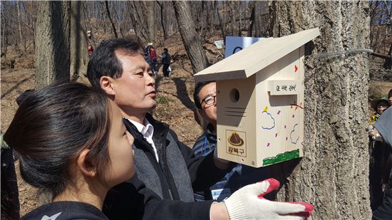 박겸수 강북구청장이 어린이들이 만든 새집을 나무에 달고 함께 살펴보고 있다.
