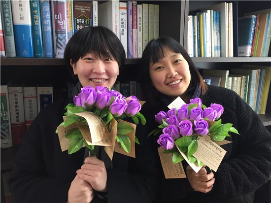 ▲시민단체 불꽃페미액션에서 활동하고 있는 대학생 이가현(오른쪽·26·여)와 김세정(25·여)씨가 세계 여성의 날을 맞아 선물 받은 꽃을 들고 기념 촬영을 하고 있다.