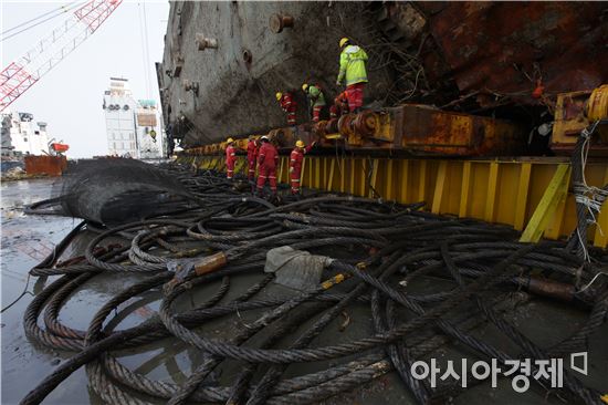 27일 세월호 선체가 선적된 반잠수식 선박에서 작업자들이 리프팅 인양와이어를 제거하고 있다.(사진:해양수산부)