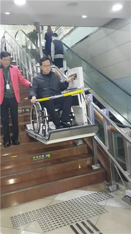 안준호 시 국장이 수동 휠체어를 타고 장애인용 리프트에 의지해 계단을 내려오고 있다. 사진=김민영 기자