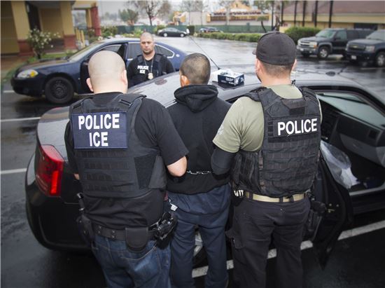 미국 이민단속국(ICE) 직원과 경찰이 지난 2월 로스엔젤레스에서 전국 단위 불법 체류자 단속 중 체포한 이를 경찰차에 태우고 있다. AP연합