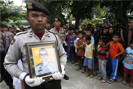 25일(현지시간) 인도네시아 경찰이 자카르타에서 발생한 폭탄 테러 사고로 희생된 동료 경찰의 영정 사진을 들고 애도하고 있다.(사진출처=EPA연합)