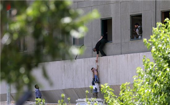 7일(현지시간) 총격·자폭테러가 발생한 이란 테헤란의 국회의사당에서 한 어린이가 주변의 도움을 받아 창문을 통해 빠져나오고 있다. (사진=EPA연합뉴스)