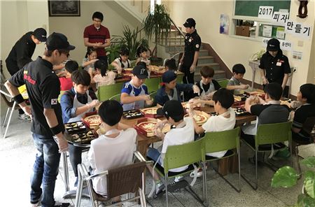 미스터피자 드림팀 원들이 14일 경기도 부천에 위치한 부천 사랑의 지역아동센터서 ‘피자 만들기 체험행사’를 하고 있다.  
