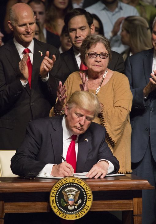 [이미지출처=연합뉴스]epa06032093 US President Donald J. Trump signs a National Security Presidential Memorandum on Cuba, after giving remarks at Manuel Artime Theater in Miami, Florida, USA on 16 June 2017. Behind Trump are, from left, Florida