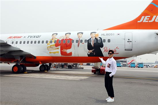 19일 동방신기의 유노윤호가 SM엔터테인먼트 제주워크숍을 떠나기 전 자신의 얼굴이 래핑된 제주항공 래핑기를 배경으로 사진촬영을 하고 있다.<사진=제주항공>