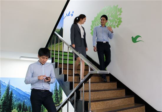 삼천리 직원들이 건강 계단을 이용하면서 동료와 이야기를 나누고 스마트폰 앱으로 자신의 운동량을 측정하고 있다.