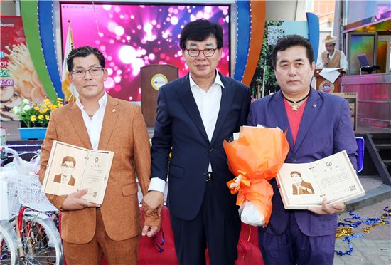 장흥토요시장 발전에 공헌한 토요시장 상인 김용만 씨(왼쪽)와 정남진이벤트기획 이병수 대표(오른쪽)가 표창장을 받고 김성 장흥군수(가운데)와 기념촬영을 하고있다.
