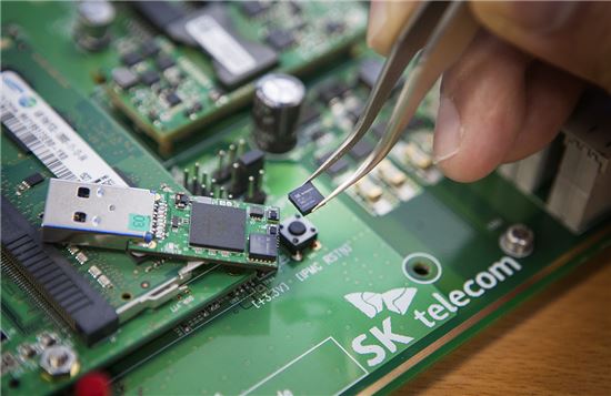 SK텔레콤 분당사옥에 위치한 '양자암호통신 국가시험망'에서 SK텔레콤 직원이 5x5mm 크기의 양자난수생성 칩을 들고 있는 모습.