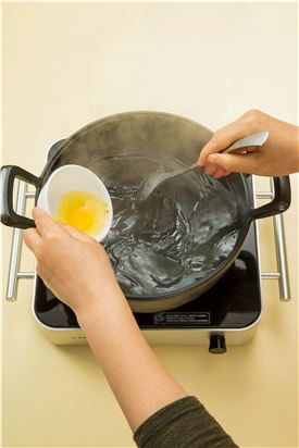 3. 끓는 물에 소금과 식초를 약간씩 넣어 물이 회오리치도록 휘휘 저어 회오리치는 물에 달걀을 넣어 노른자가 반숙이 되도록 익혀 거름망으로 건진다.