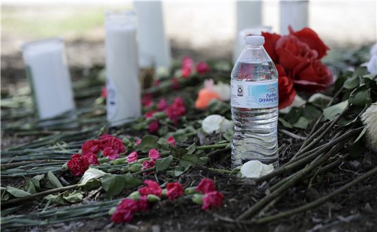 트레일러를 타고 밀입국을 시도하다 수십명의 사상자가 발생한 가운데 24일(현지시간) 이들이 발견된 미국 텍사스주 샌안토니오의 도로변 월마트 주차장에 시민들이 놓아 둔 물병과 꽃이 있다. (사진=AP연합뉴스)