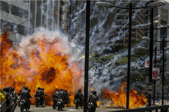 30일(현지시간) 베네수엘라 수도 카라카스에서 사제폭탄이 폭발해 시위 진압을 위해 오토바이를 타고 이동 중인 기동경찰대를 덮치고 있다. (사진=EPA연합뉴스)