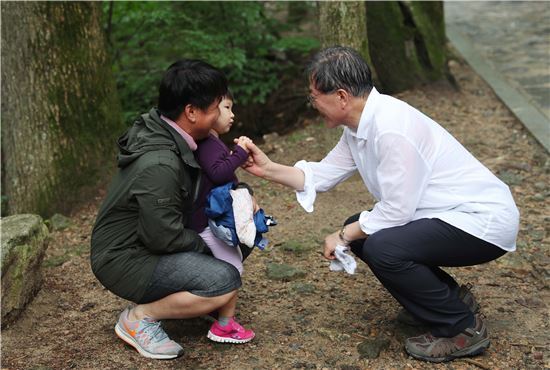 문재인 대통령이 휴가 2일차인 지난달 31일 강원도 평창 오대산에서 어린아이를 만나 무릎을 굽히고 인사하고 있다. (사진=청와대)