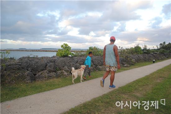 ▲통가의 한 시민이 아이와 함께 바닷가를 산책하고 있다.
