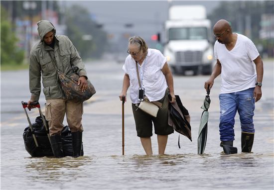 27일(현지시간) 허리케인 하비가 쓸고 간 미국 텍사스주에서 일가족이 발목까지 빗물이 차오른 도로를 걸어 대피하고 있다. (사진출처=EPA연합)