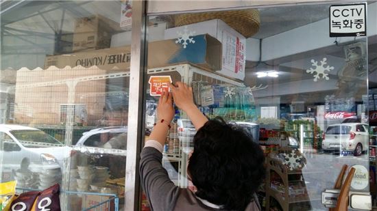 올해 생명지킴이활동가가 지역 내 번개탄 판매 소매업소를 대상으로 희망판매소 인증 스티커를 부착하는 모습