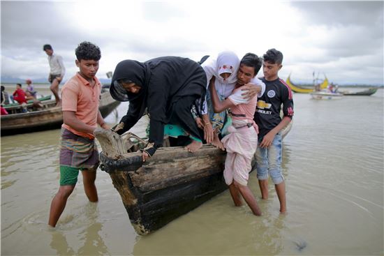 지난달 31일(현지시간) 방글라데시 텍낙 운하에서 배를 타고 국경을 넘어온 로힝야족 사람들이 부축을 받고 있다.(사진출처=AP연합)  