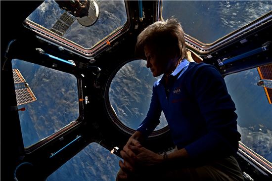 ▲일곱 개의 창으로 이뤄진 우주전망대 '큐폴라'에서 페기 윗슨이 지구를 배경으로 사진을 촬영했다.[사진제공=NASA]