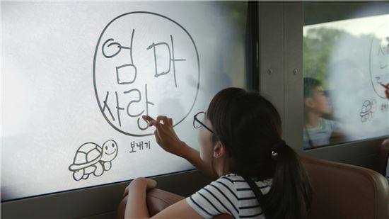 통학버스에 구현된 '스케치북 윈도우' 기술을 이용해 창문에 글을 쓰고 있는 어린이의 모습
