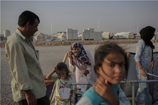 지난 7월 말 이라크 북부 하산 섐 캠프에서 난민 가족들이 줄을 서서 물 배급을 받고 있다. (사진출처=AP연합)