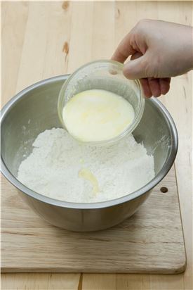 3. 볼에 옮겨 담고 양손으로 가볍게 비빈 뒤 차가운 우유와 요구르트, 달걀노른자 섞은 것을 3~4회에 나누어 넣으면서 스크래퍼로 가볍게 섞는다.
