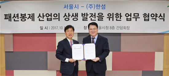 김민덕 한섬 부사장(사진 오른쪽)과 서동록 서울시 경제진흥본부장(사진 왼쪽)이 서울시청 본관에서 업무 협약(MOU)을 체결하고 기념 촬영을 하고 있는 모습.