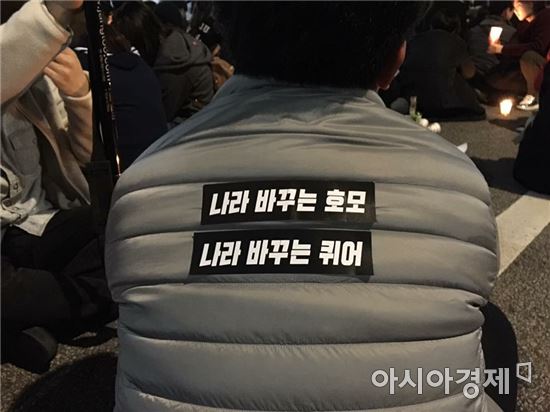 강명진 퀴어문화축제조직위원회 조직위원장이 '나라 바꾸는 호모' '나라 바꾸는 퀴어'라고 적힌 패딩을 입고 촛불집회를 지켜보고 있다. 사진제공=강명진씨
