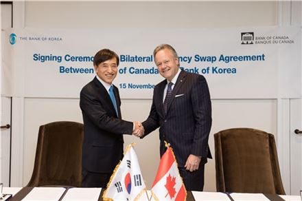 이주열 한국은행 총재(왼쪽)가 15일 오후(현지 시간) 캐나다 오타와에 위치한 캐나다중앙은행 본부에서 스티븐 폴로즈 캐나다중앙은행 총재와 양국간 통화스와프 협약서에 서명한 뒤 악수하고 있다. (캐나다중앙은행 제공)