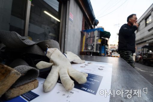 충무로 인쇄골목에서 한 인쇄물 배달원이 삼륜 오토바이 위에 장갑을 벗어둔 채 휴식을 취하고 있다. 