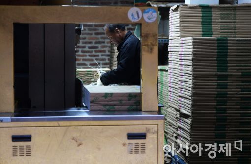 충무로 인쇄골목에서 한 업자가 거래처의 즉각적인 주문에 맞춰 신속하게 종이를 재단하고 있다.