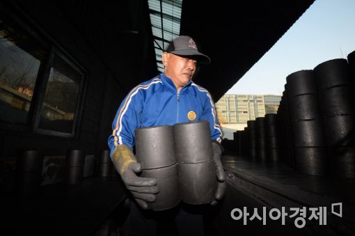연탄공장에서 한 도매업자가 연탄을 차량에 싣고 있다.