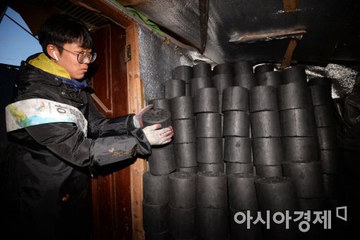 노원구선거관리위원회 자원봉사자가 에너지 소외 가구의 창고에 연탄을 차곡차곡 쌓고 있다.