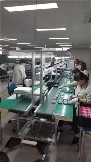 팅크웨어 충주 공장 내 직원들이 내비게이션 제품을 조립하고 있다.