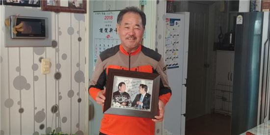 김재수씨가 2007년 2월 토비 도슨 프리스타일 스키 대표팀 감독과 상봉했을 당시 찍은 사진을 들고 웃고 있다 [사진=김형민 기자]