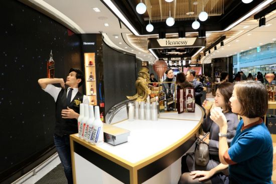롯데면세점 인천공항 제2터미널점 주류 · 담배  플래그십 매장을 방문한 고객들이 전문 바텐더의 공연을 보며 칵테일 시음을 하고 있다.
