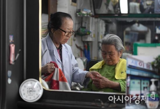 이발을 마친 손님에게 사탕을 건넨 이덕훈 할머니는 요금으로 2천원만 받았다./김현민 기자 kimhyun81@
