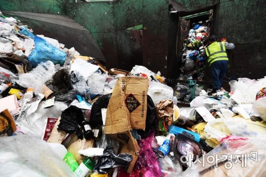 재활용 처리시설에서 한 근로자가 쓰레기들을 컨베이어 벨트 위로 옮기고 있다. /문호남 기자 munonam@
