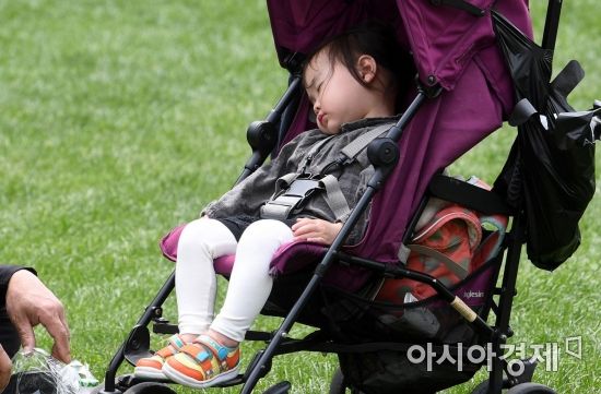 한 아이가 유모차에서 낮잠을 자고 있다.