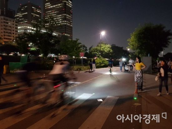 지난 8일 밤 여의도 한강공원에서 자전거를 탄 시민들이 보행자 사이를 지나고 있다.